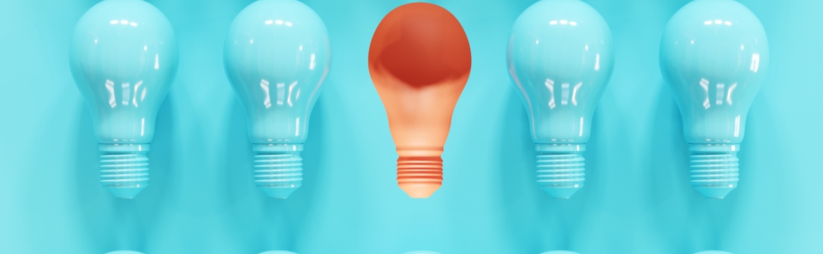 Blue light bulbs on blue background with one orange light bulb in the centre.