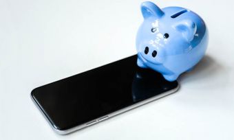 A blue piggy bank next to a mobile phone