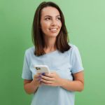 Young woman uisng phone with green background