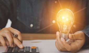 Man holding lightbulb and calculator.