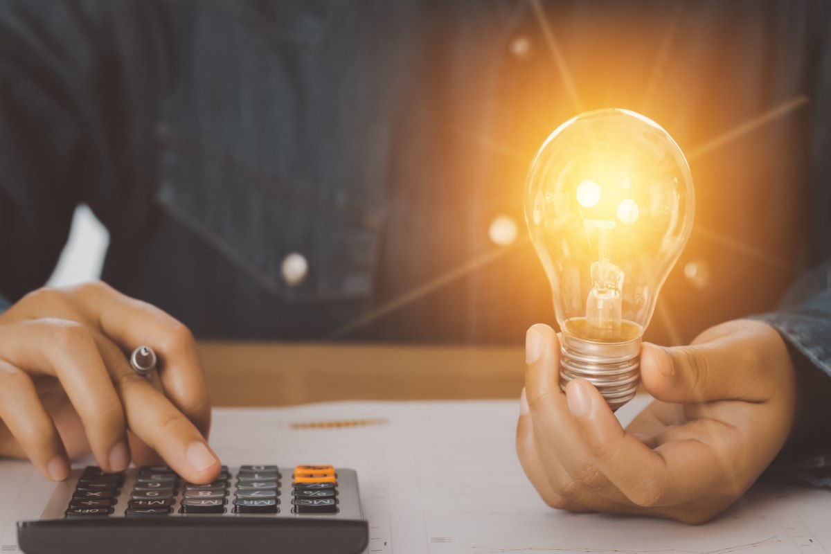 Man holding lightbulb and calculator.