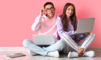 Young couple using laptop in pink room