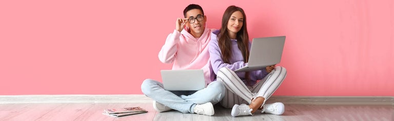Young couple using laptop in pink room