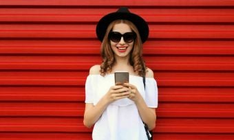 Happy woman using smartphone with red background