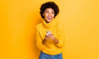 Woman holding phone against yellow background