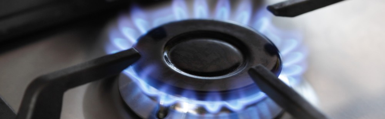Natural gas stove top with flame on.