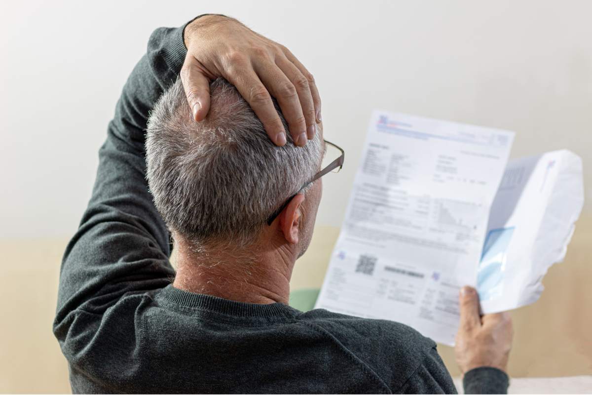 Stressed older man looking at his energy bill.