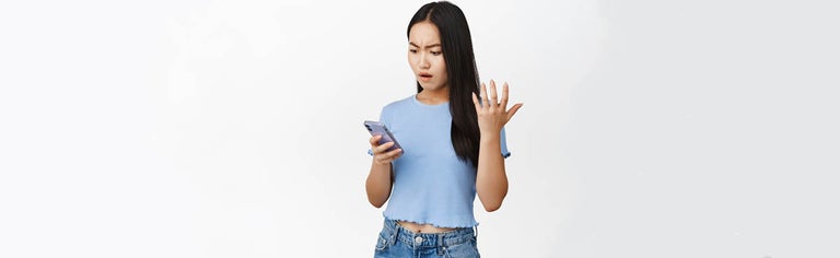 Young woman looking at smartphone angrily