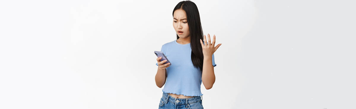 Young woman looking at smartphone angrily