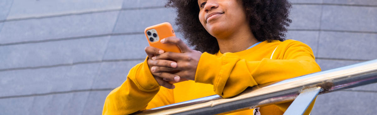 Young woman in yellow jumper using mobile phone