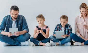 Family of four using phones and tablets together