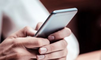 Person holding phone infront of laptop