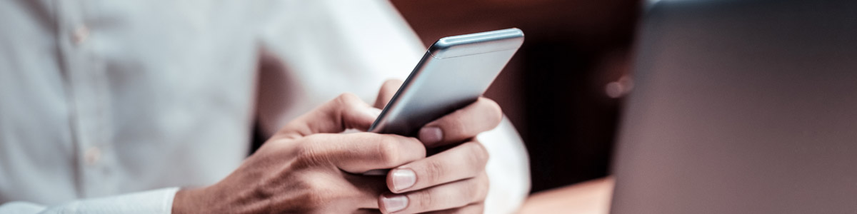 Person holding phone infront of laptop