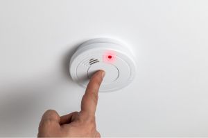 Hand turning on smoke alarm in home.