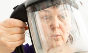 Woman looking at limescale on kettle