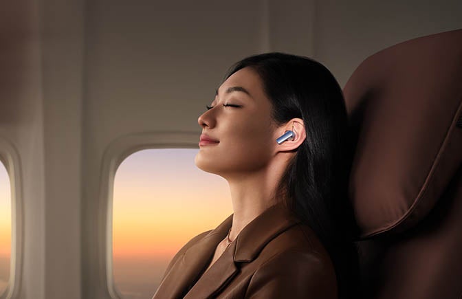 Woman relaxing on airplane wearing Huawei earbuds 