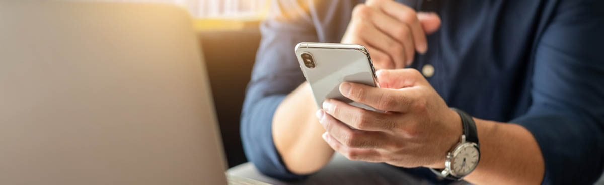 Man using mobile phone while on laptop