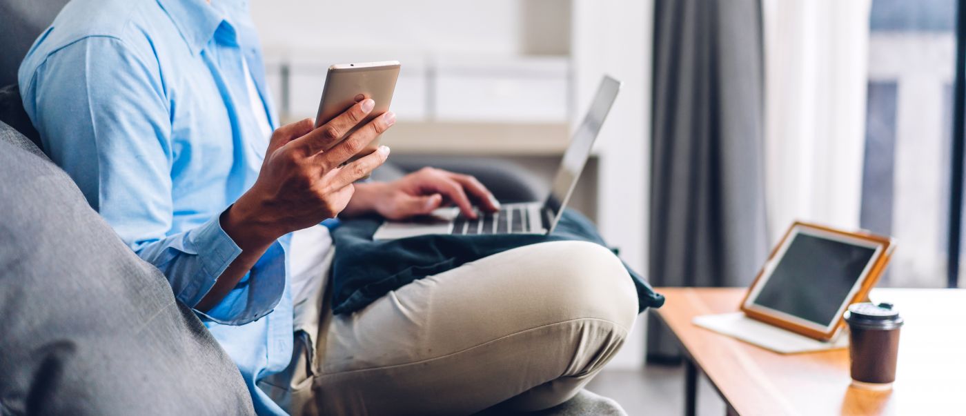 Man holding phone and working on laptop