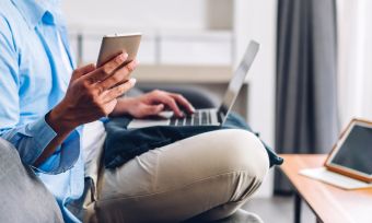 Man holding phone and working on laptop