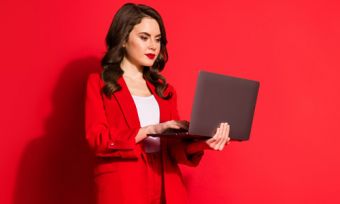 Woman holding laptop against red background