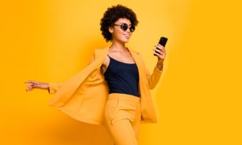 Woman wearing yellow holding phone in front of yellow background