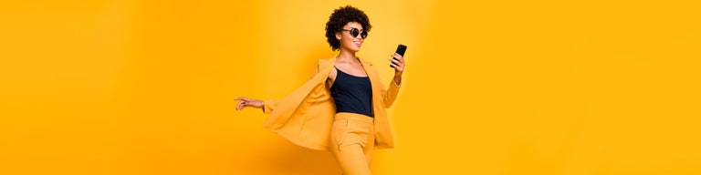 Woman wearing yellow holding phone in front of yellow background
