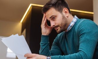 Stressed man looking at energy bill.