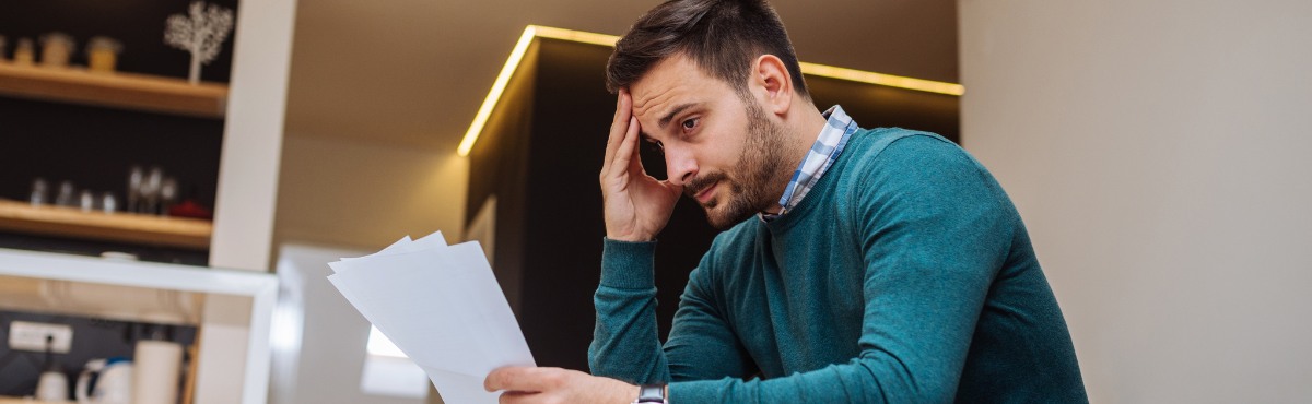 Stressed man looking at energy bill.