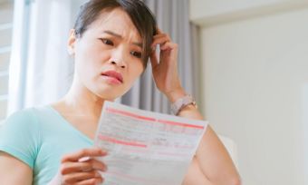 Woman confused by power bill in living room.