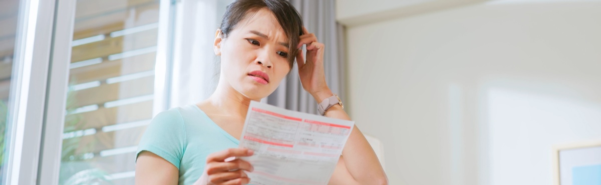 Woman confused by power bill in living room.