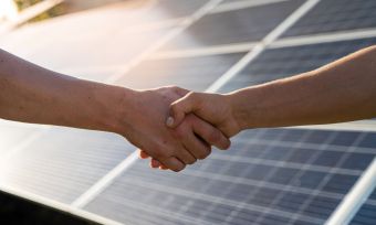shaking hands with solar panels in the background