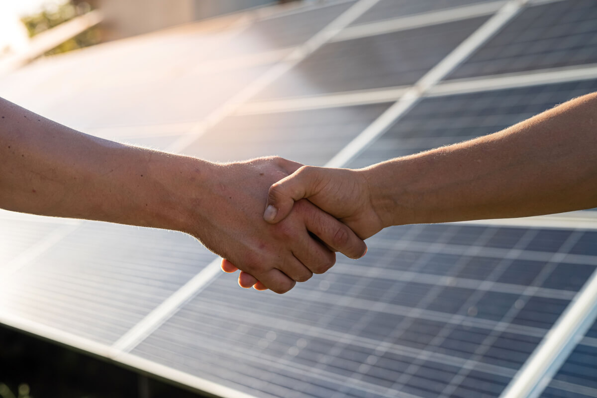 shaking hands with solar panels in the background