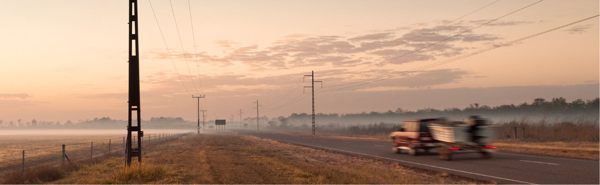 Dirt road in Darwin with car speeding past.