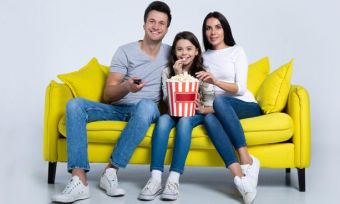 Family watching move together on yellow couch