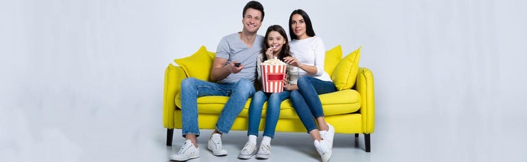 Family watching move together on yellow couch