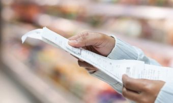 Woman staring at receipt in an aisle at the grocery store.