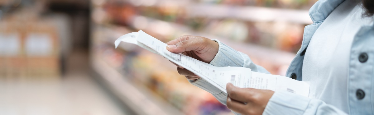 Woman staring at receipt in an aisle at the grocery store.