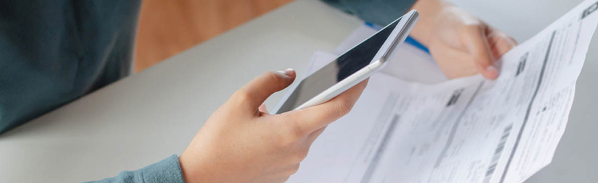 Closeup on person paying bills with smartphone