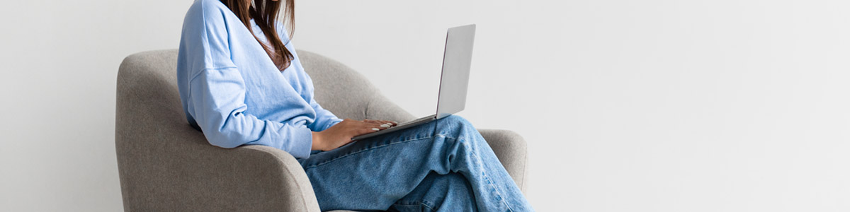 Woman on armchair looking at laptop