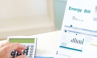 Man looking at energy bill with calculator on desk.