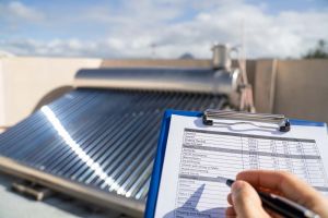 Man with clipboard checking evacuated solar tube panel.