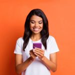 Woman looking at phone against orange background