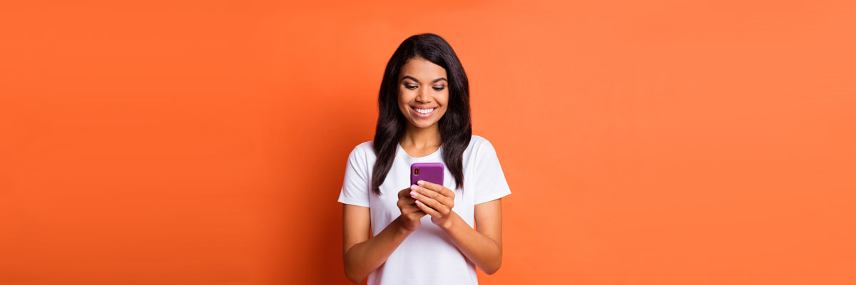 Woman looking at phone against orange background