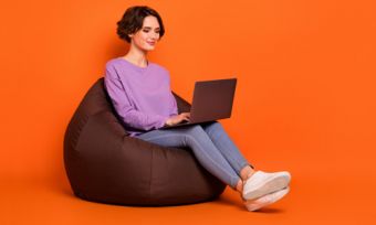 Woman looking at laptop against orange background