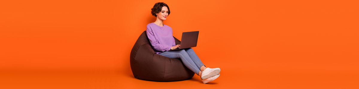 Woman looking at laptop against orange background