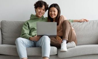 Happy young couple using laptop on couch