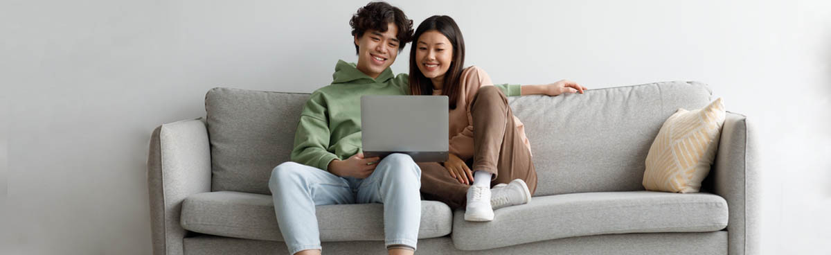 Happy young couple using laptop on couch