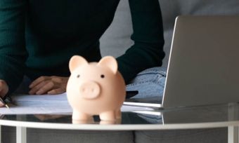 Woman using laptop to pay bills with piggy bank