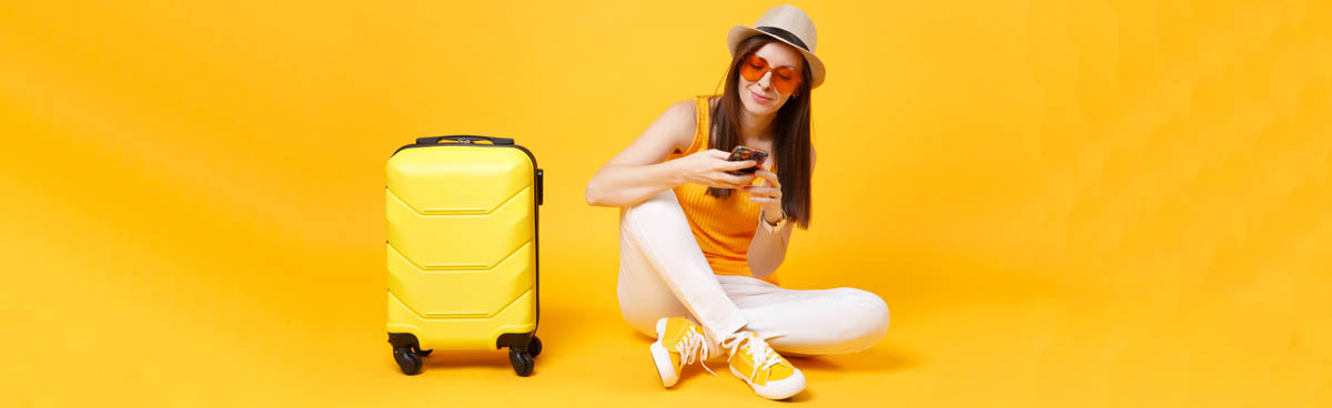 Woman with suitcase and orange outfit using phone