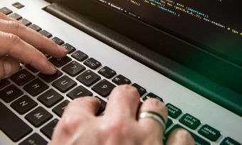 Close up of hands on keyboard typing code